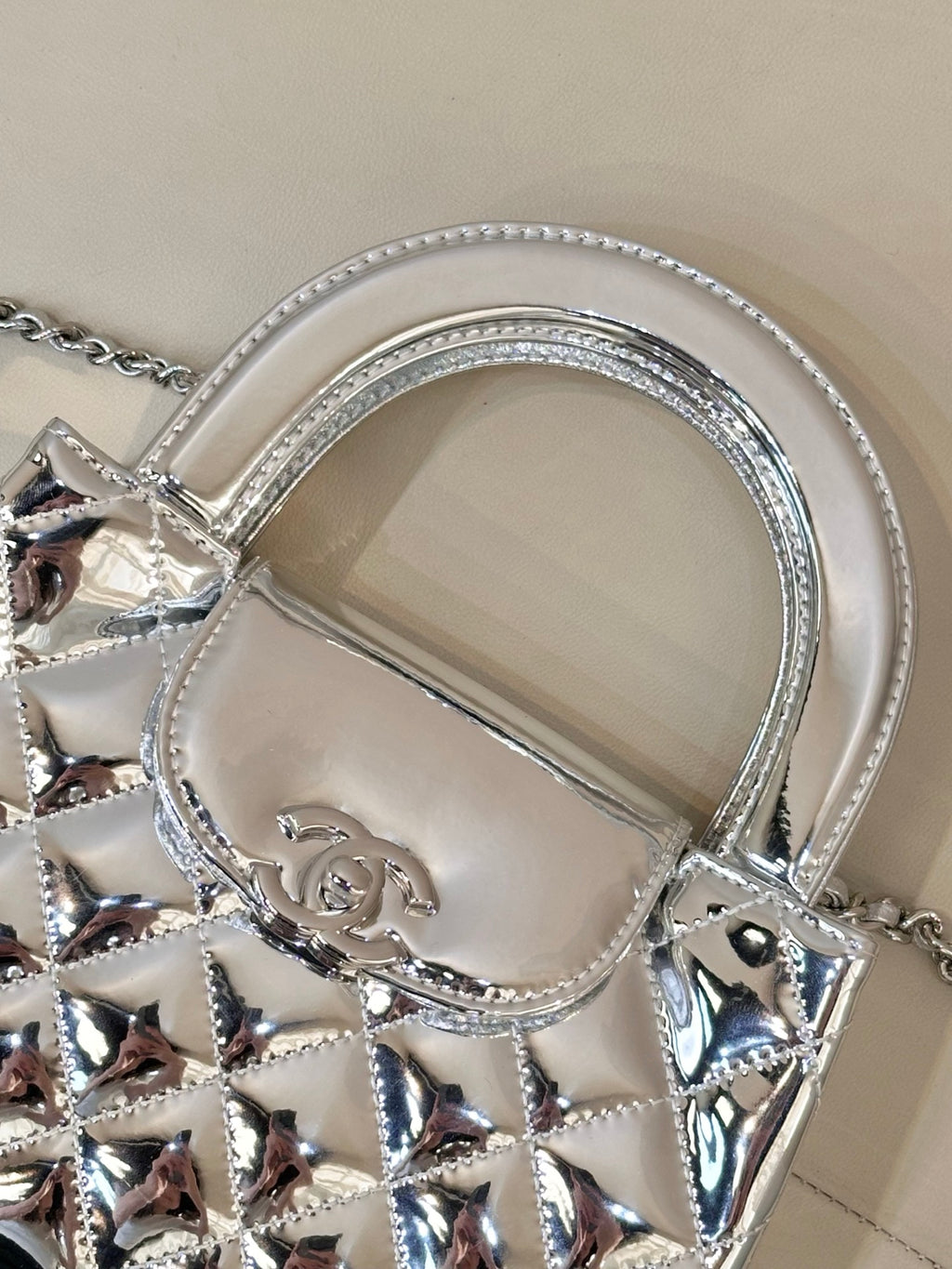 Chanel silver quilted bag detail: arched top handle, logo plaque, chain links