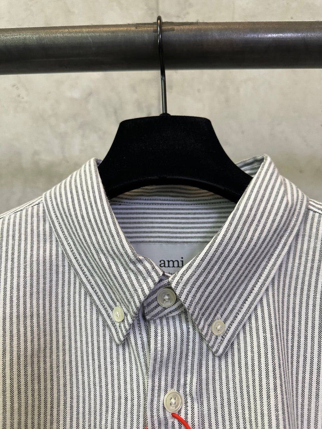 Close-up of striped button-up shirt collar with buttons and small chest logo patch