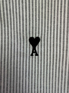 Striped shirt fabric detail with small black heart-shaped A logo on chest