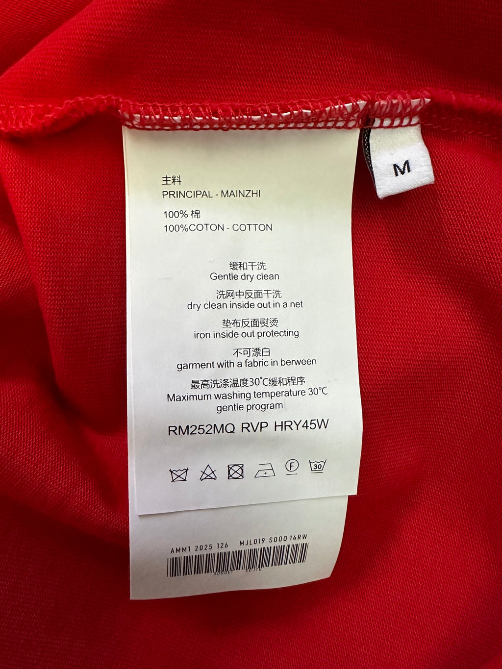 Red T-shirt care label: size M, 100% cotton, gentle dry clean instructions.