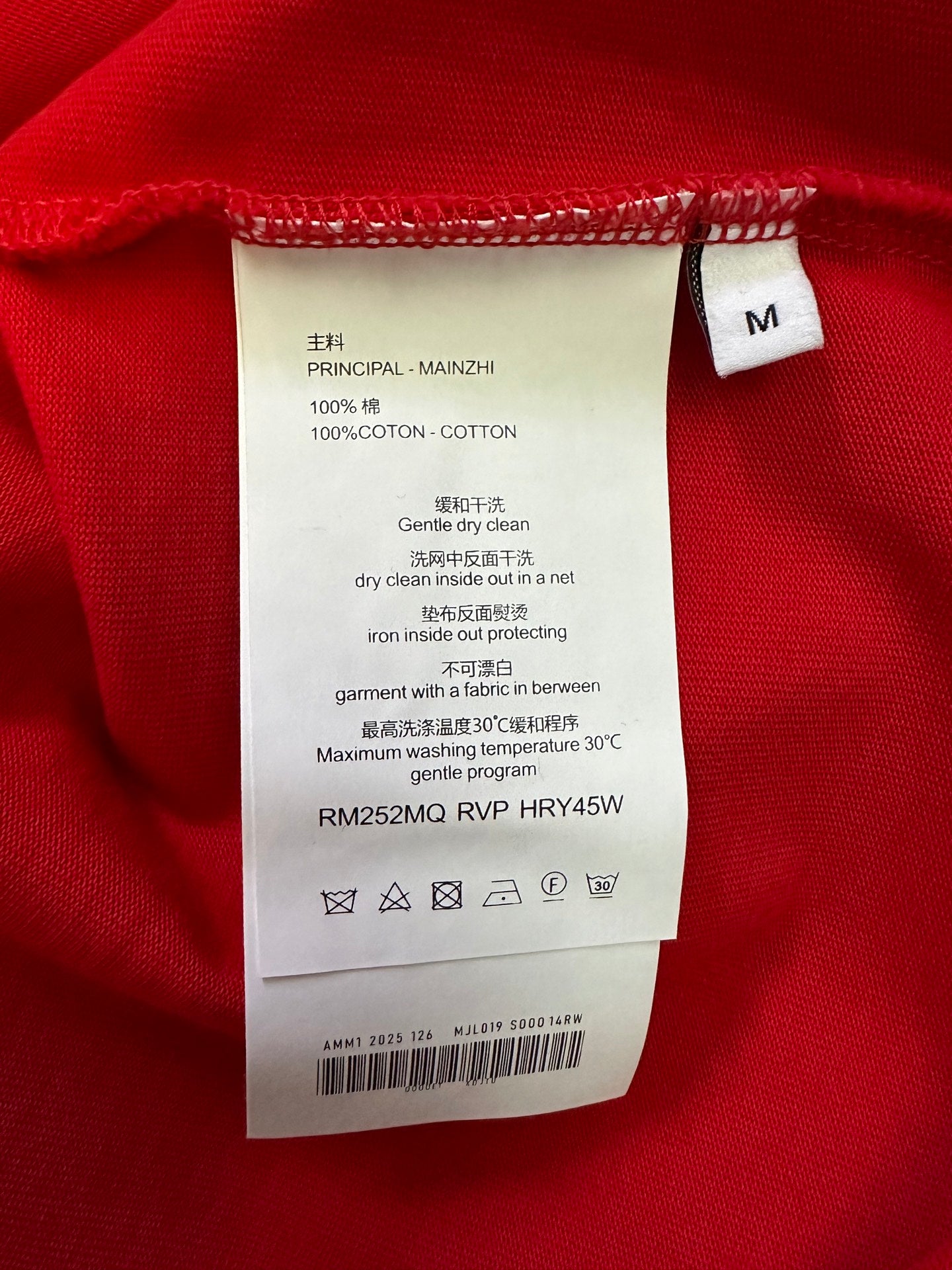 Red T-shirt care label: size M, 100% cotton, gentle dry clean instructions.