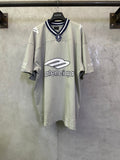 Light sage short-sleeve T-shirt with navy striped collar and crest patch at neckline