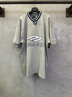 Light sage short-sleeve T-shirt with navy striped collar and crest patch at neckline