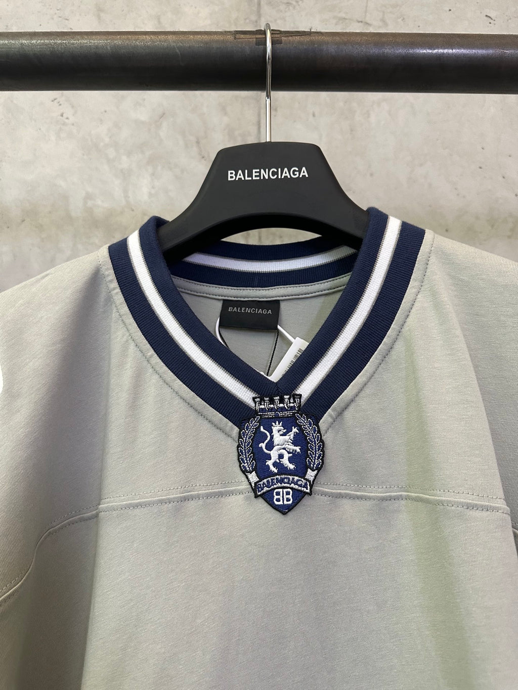 Close-up light sage short-sleeve T-shirt neckline with navy striped trim and crest