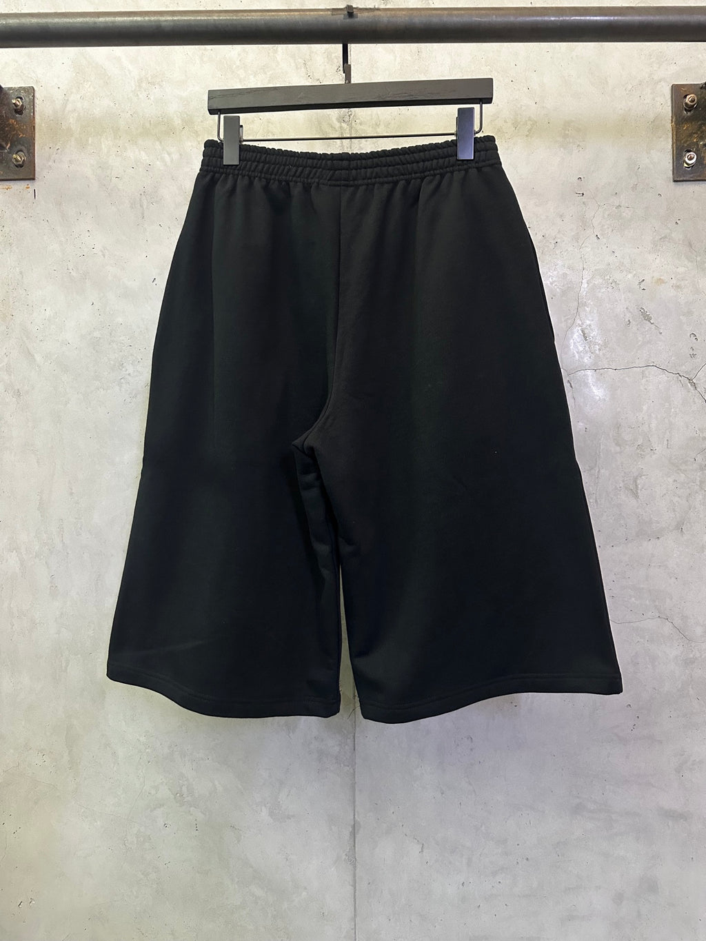 Black drawstring shorts with elastic waistband, relaxed straight legs, side slit pockets.