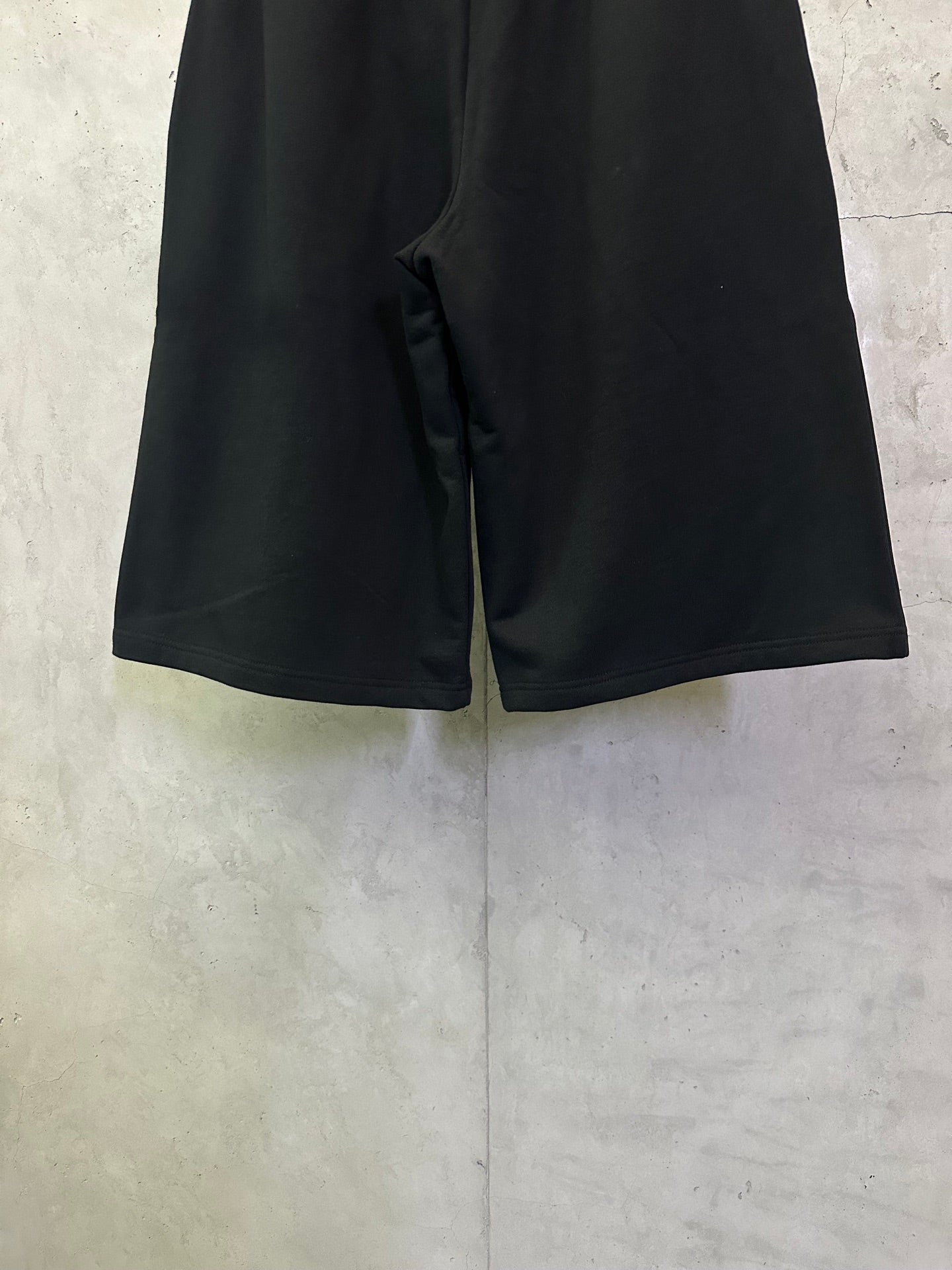 Black shorts with elastic waistband and side pockets, curved seam detail at front.