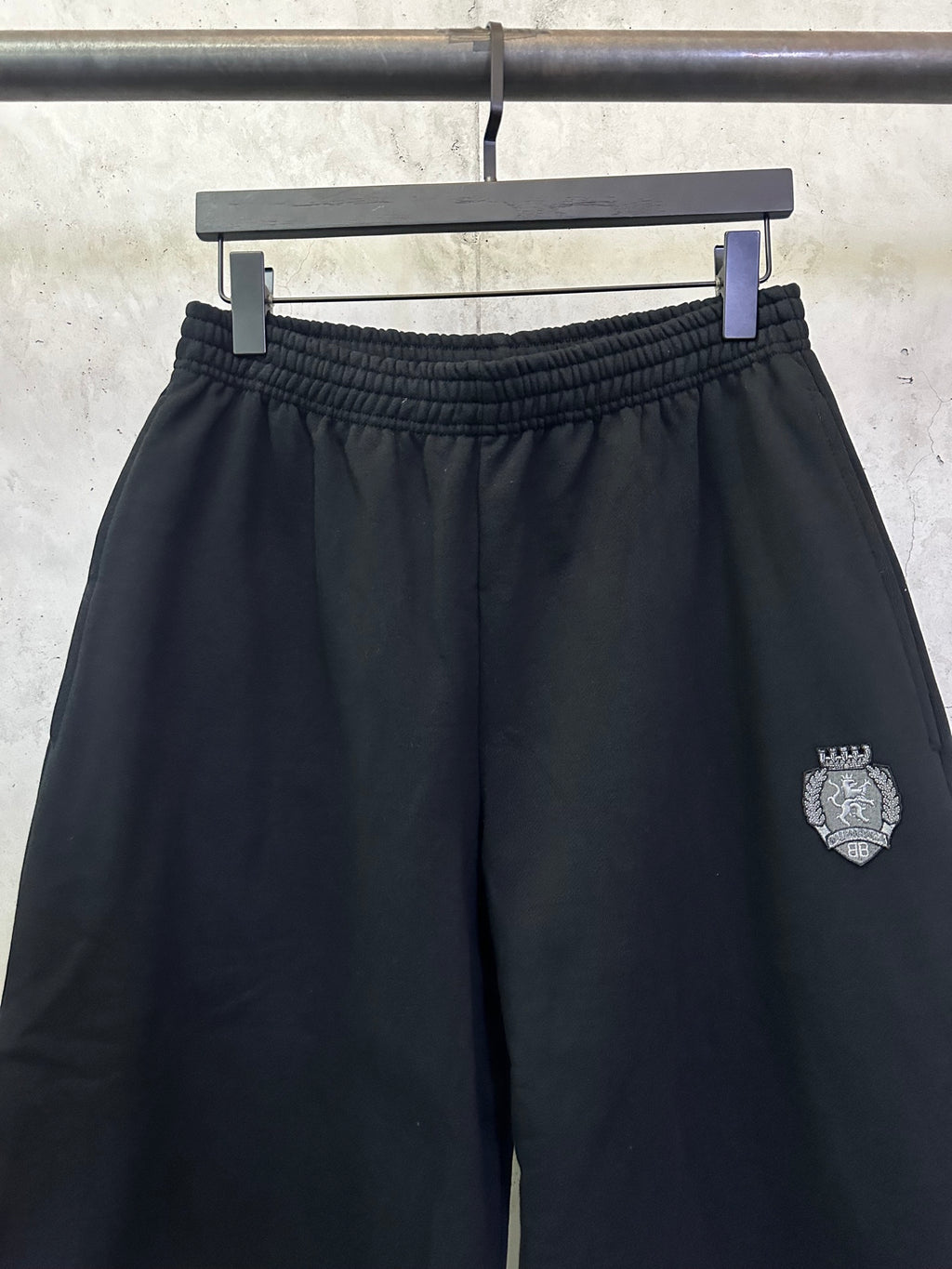 Black shorts with elastic waistband and side logo crest patch on the right leg.
