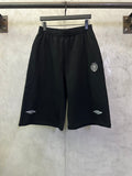 Black drawstring shorts with elastic waistband and side slit pockets, small logo detail.