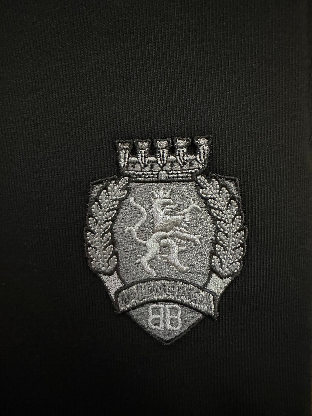 Black shorts crest logo patch with detailed silver-toned embroidery