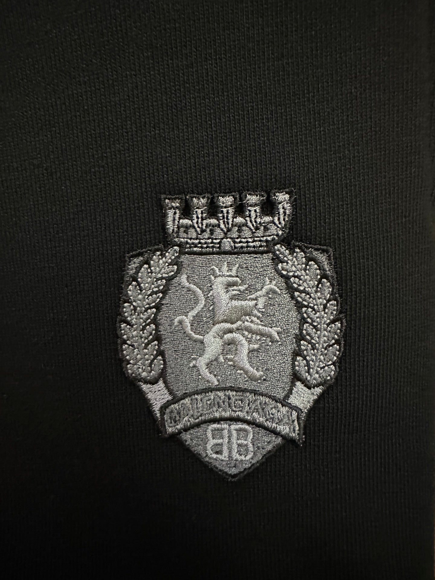 Black shorts with embroidered gray crest logo patch on the fabric.
