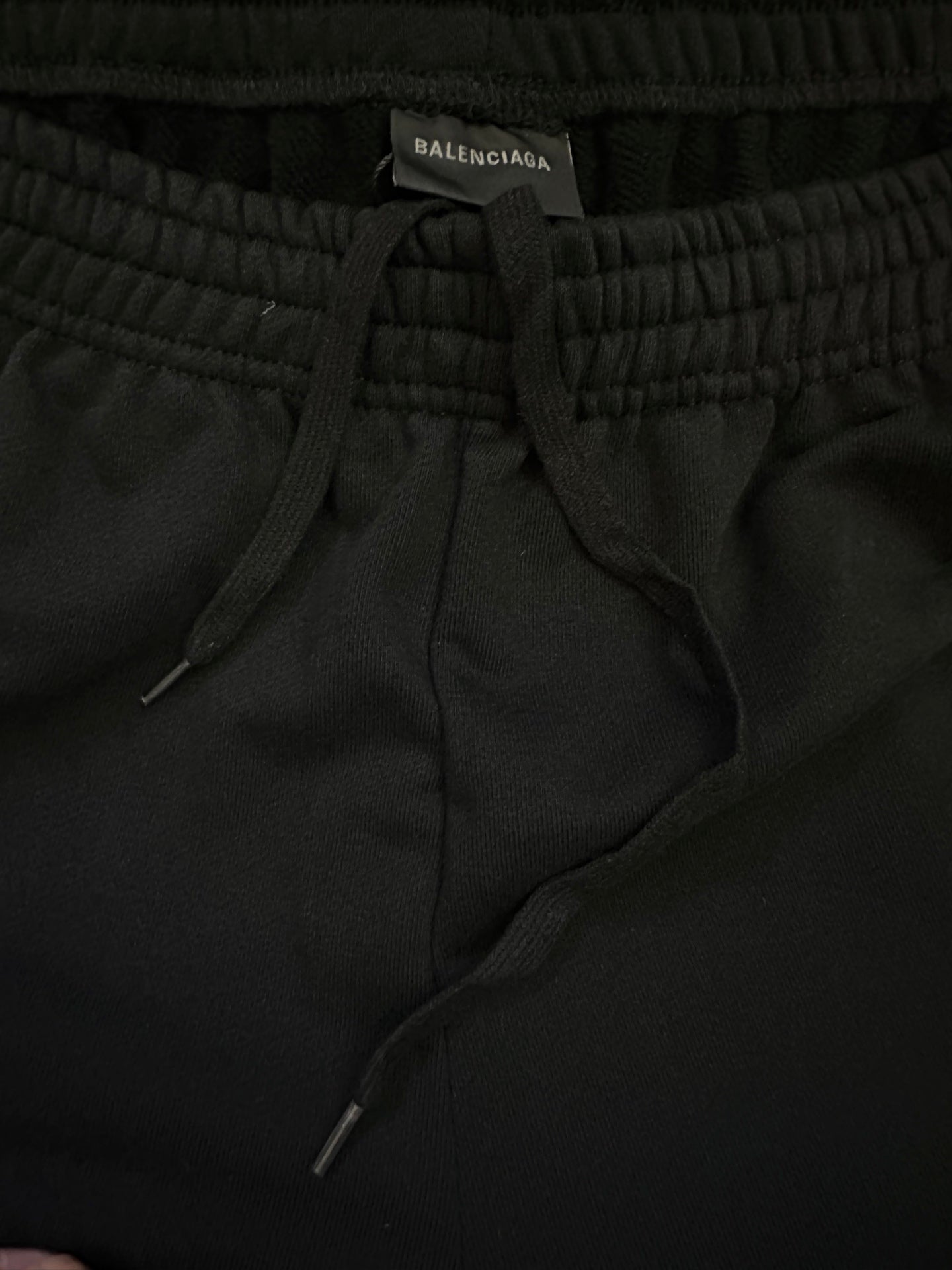 Black shorts close-up of elastic waistband with drawstring and side pocket openings.