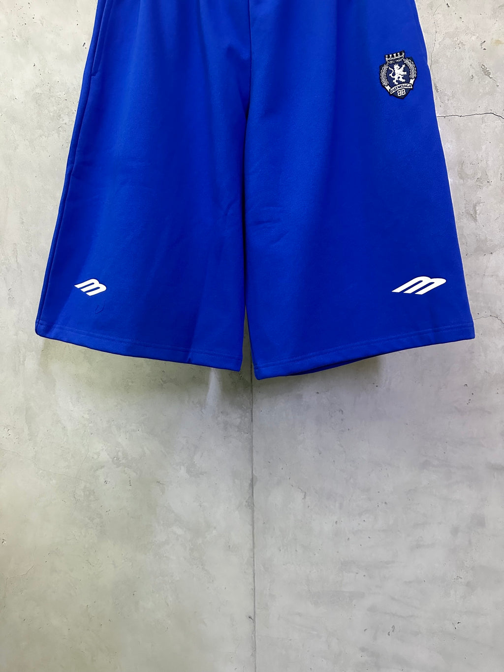 Royal blue shorts with elastic waist and side logo markings at hem