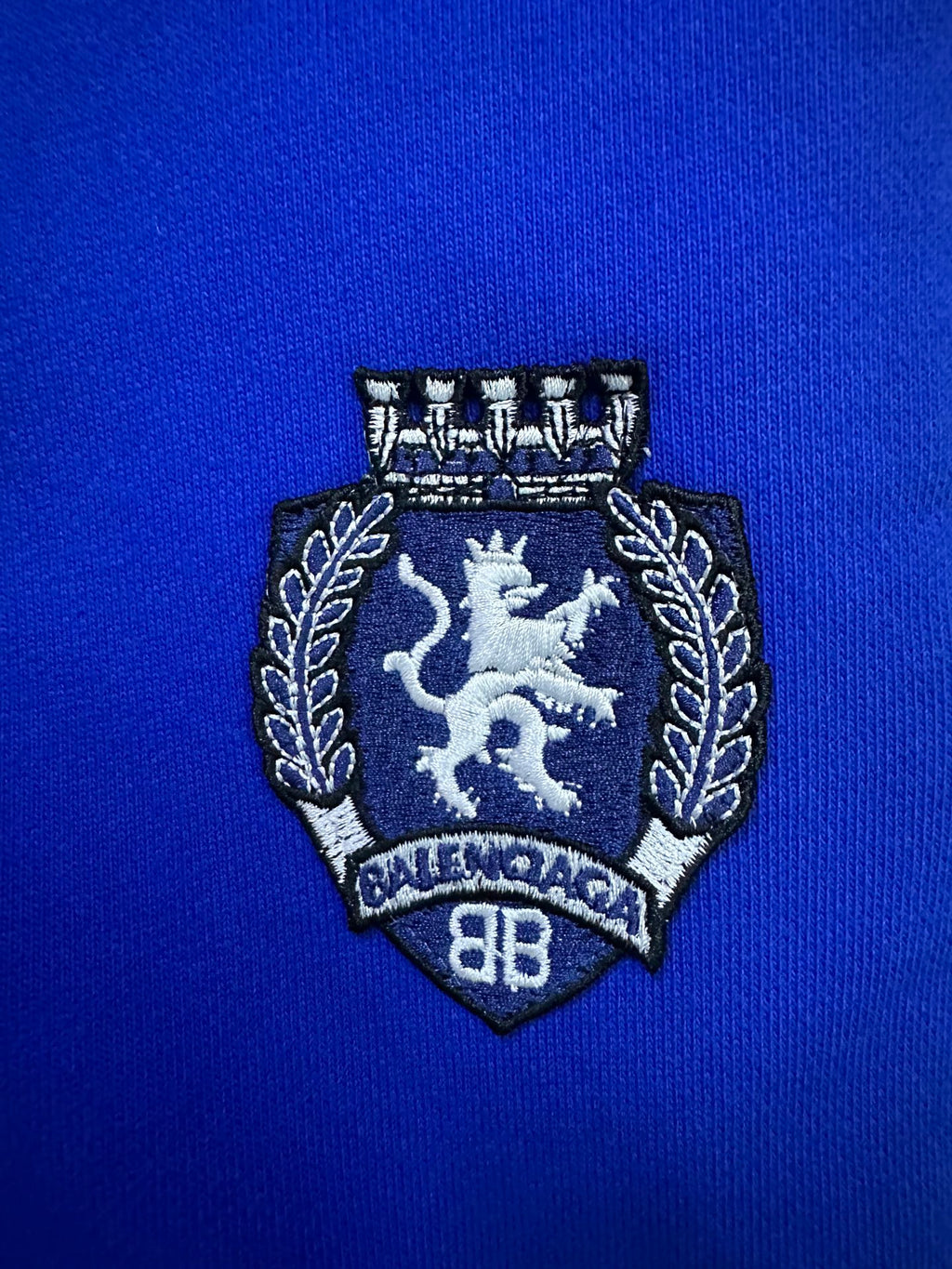 Embroidered crest patch on blue shorts