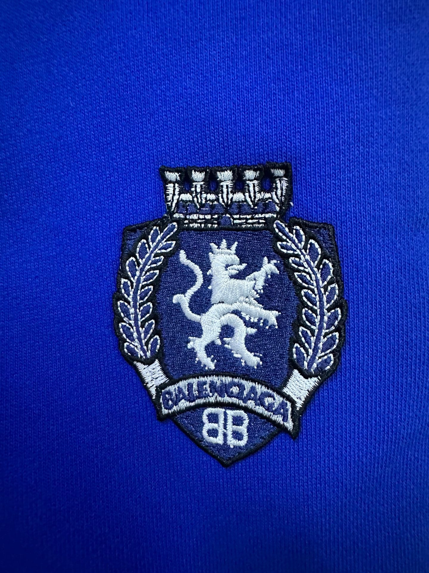 Embroidered crest patch on blue shorts
