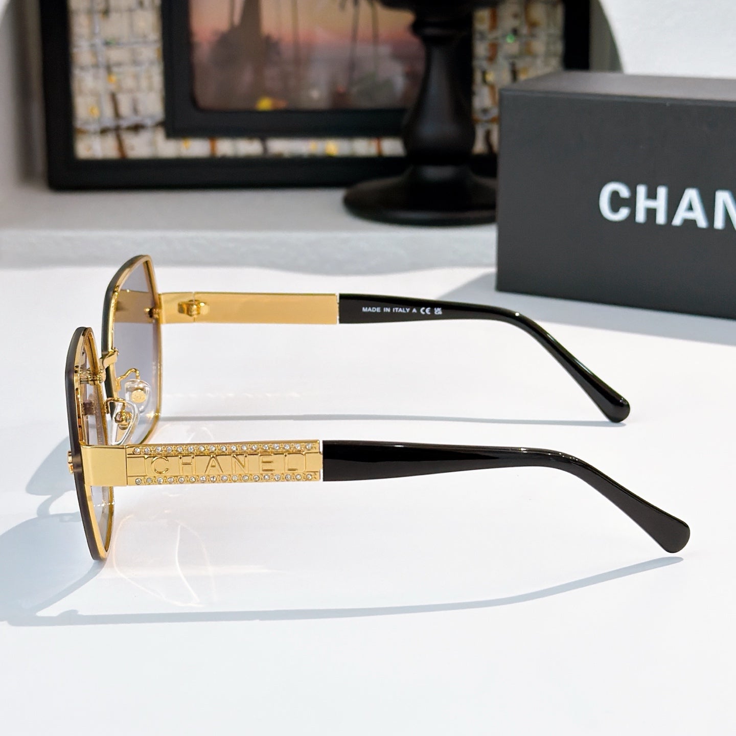 Sunglasses side view with gold-tone frame and tinted lenses, black temples.