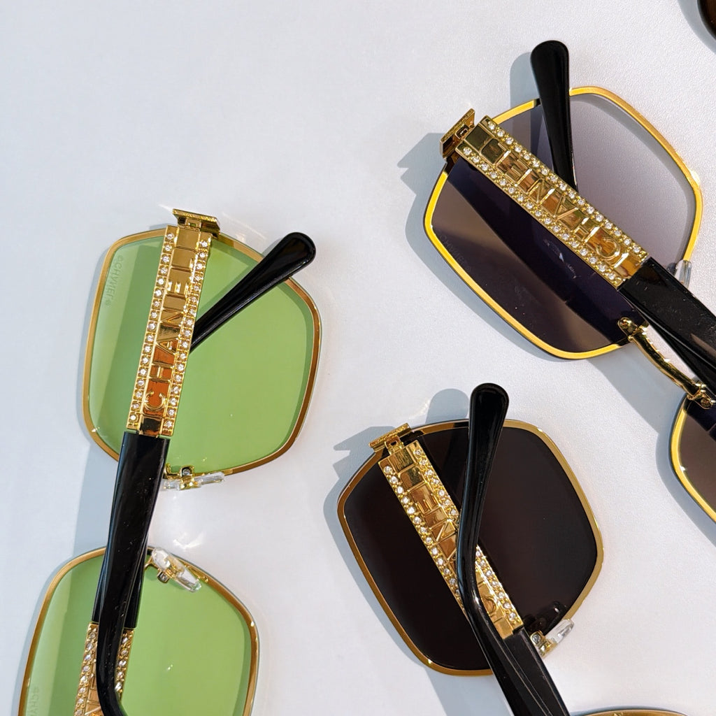 Sunglasses close-up set: green and black tinted square lenses with gold studded temple bars.