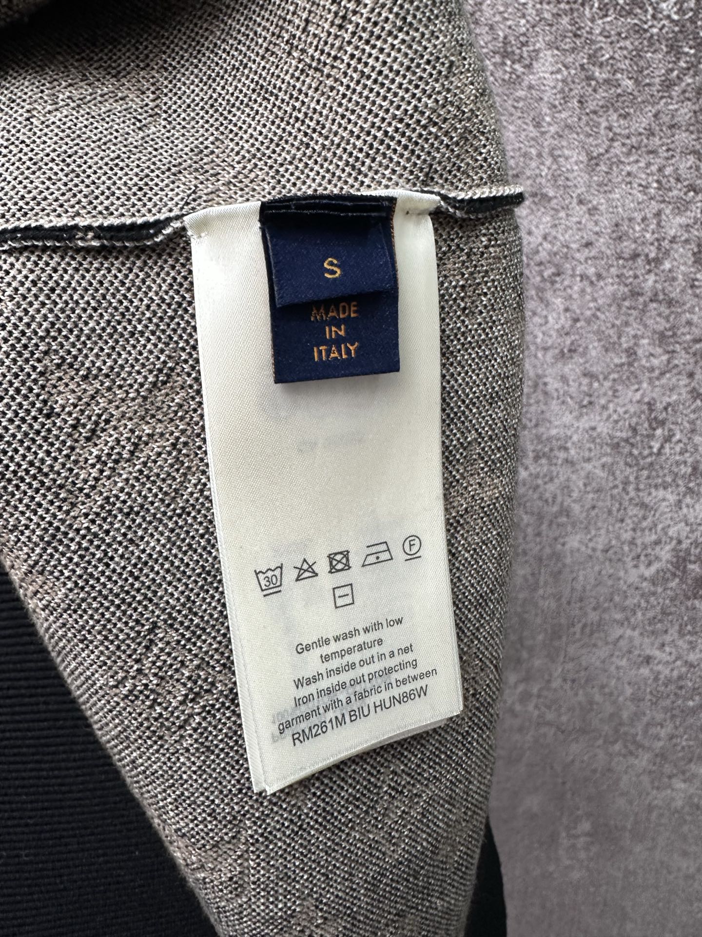 Inside neck label and care tag on knit sweater, with made in Italy text