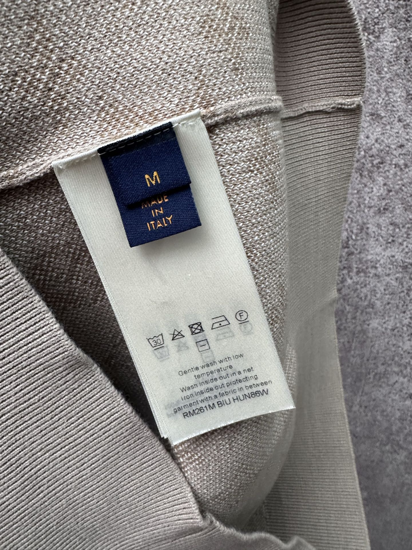 Interior neck label on light beige long-sleeve sweatshirt, size M in navy tag