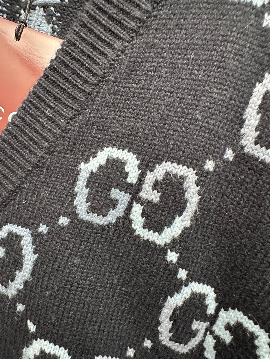 Gucci knit cardigan close-up of GG logo pattern on dark fabric