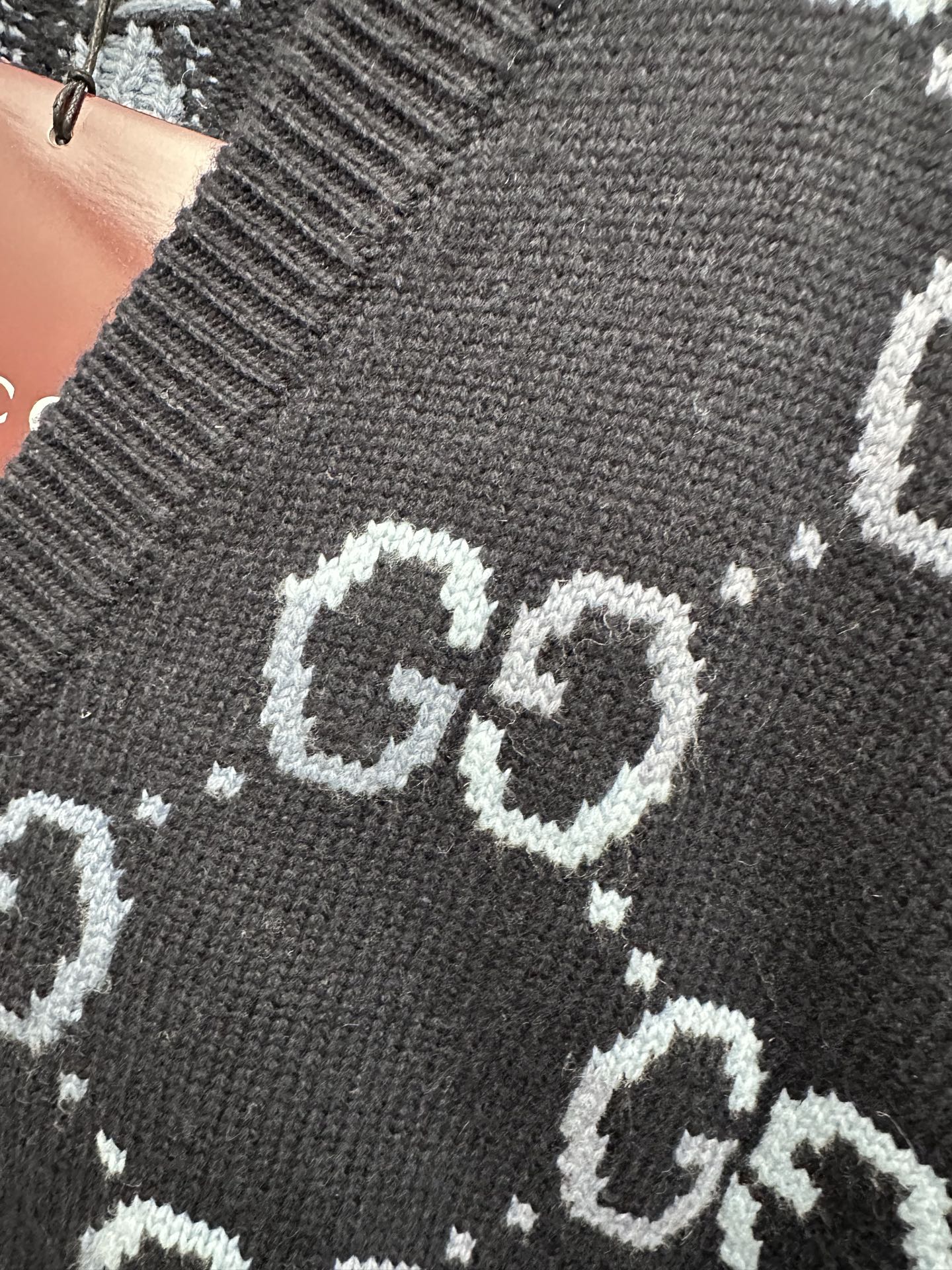 Gucci knit cardigan close-up of GG logo pattern on dark fabric