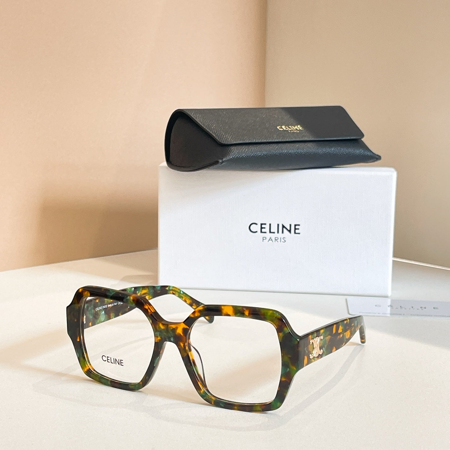 Square eyeglasses with tortoiseshell frames and gold temple emblem