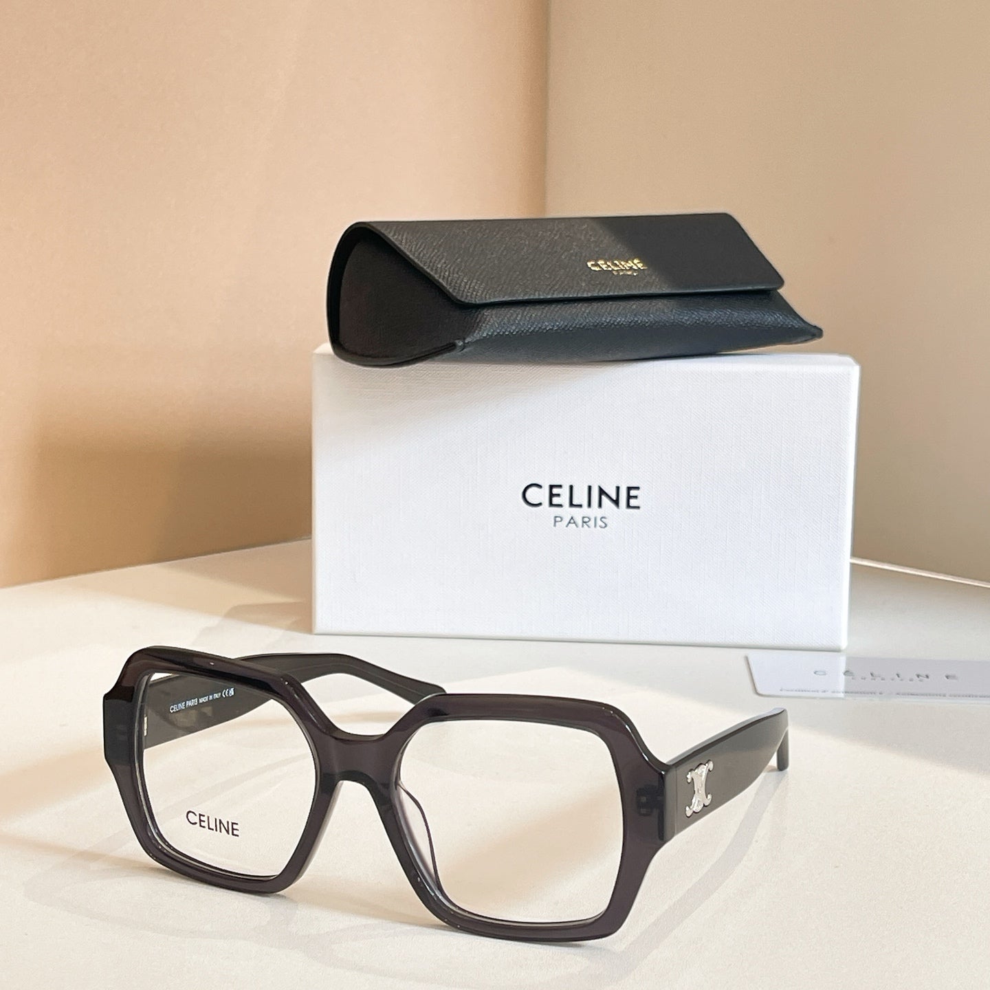 Square eyeglasses with black frames and gold temple emblem details