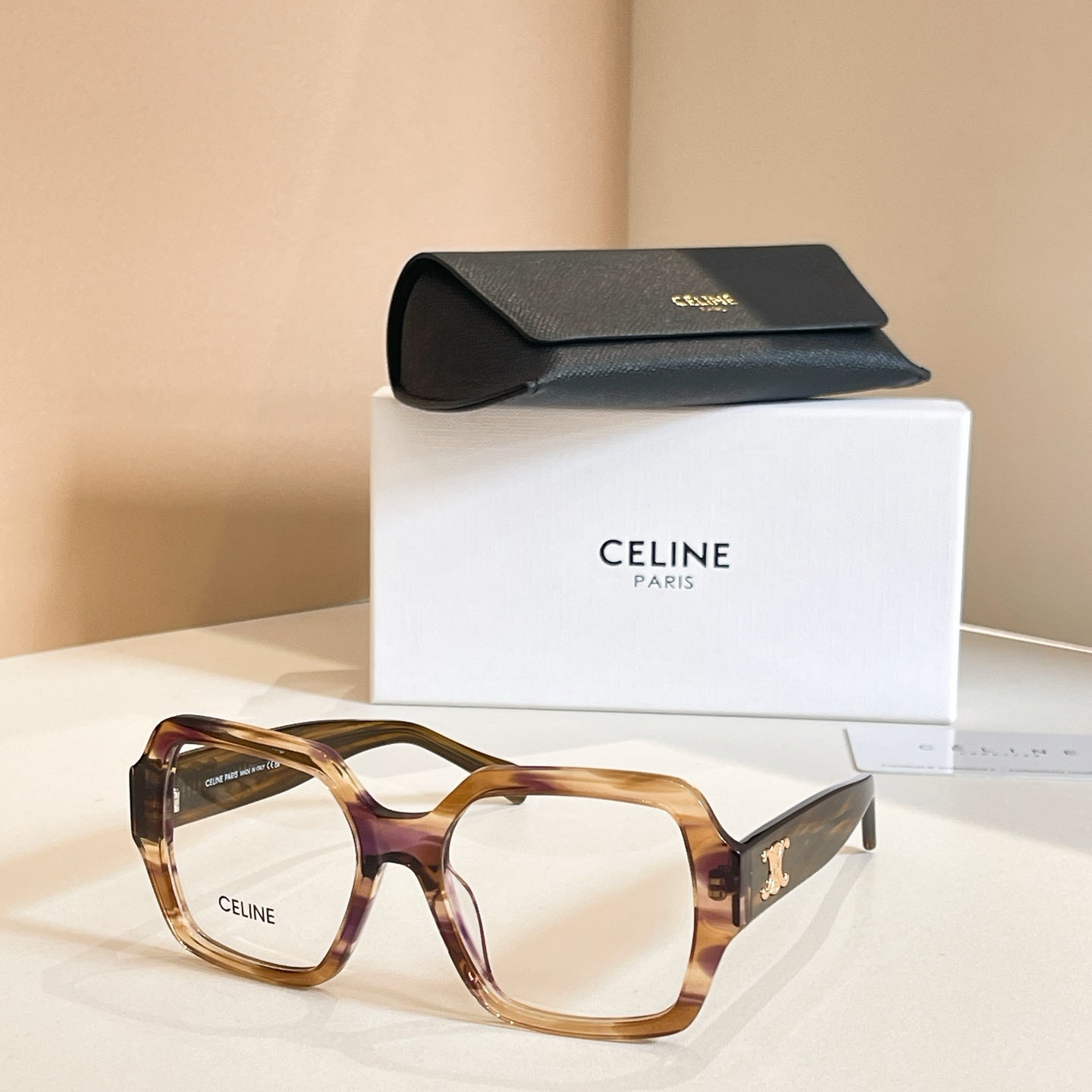 Square eyeglasses with amber frames and gold temple emblem details