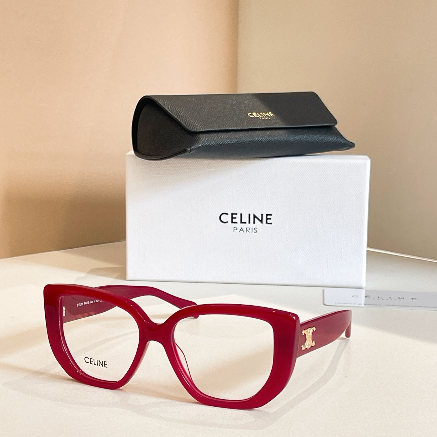 Celine glasses with red square frames and clear lenses, gold temple detail.