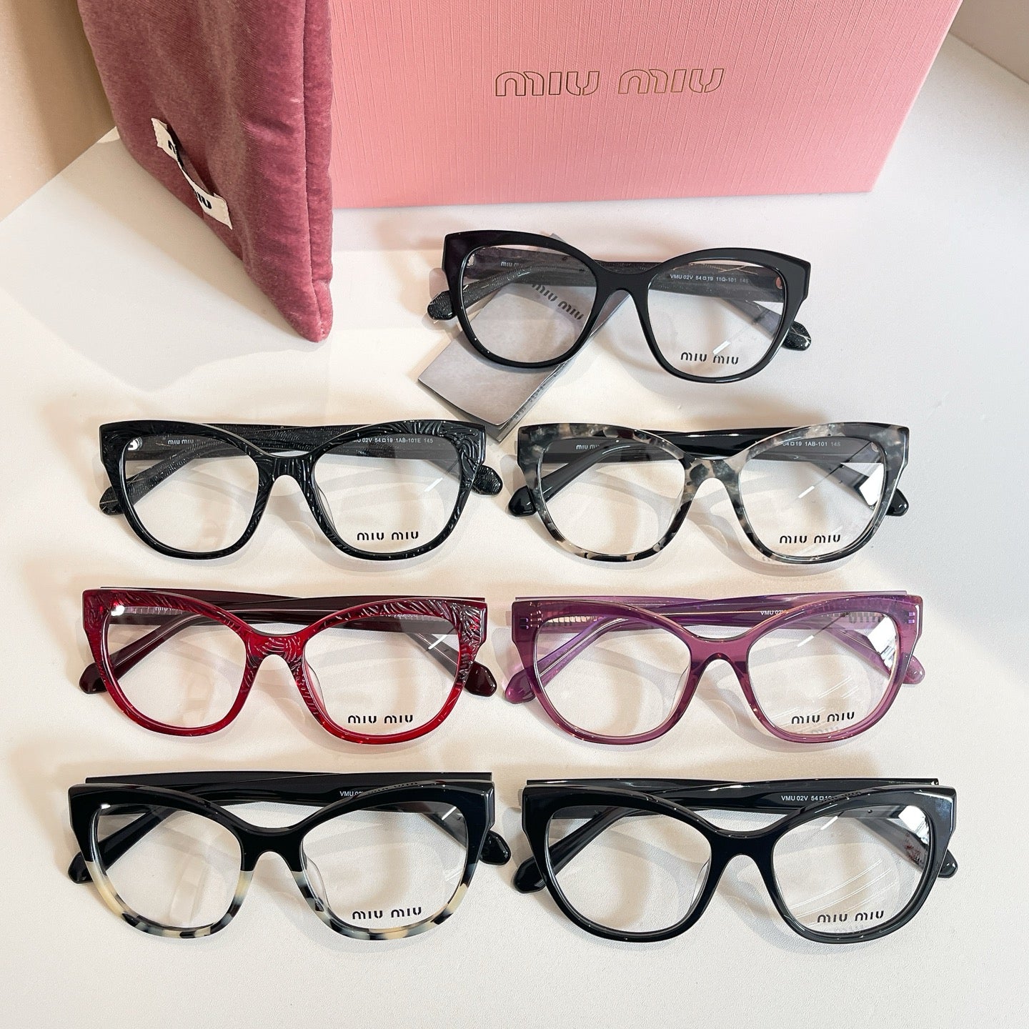 Set of MiuMiu eyeglasses with black, burgundy, and purple frames, clear lenses, logo temples