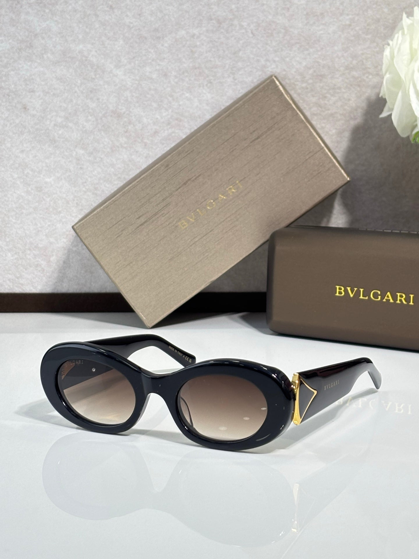 Bvlgari sunglasses with black frames and dark lenses, gold-trim temple detail