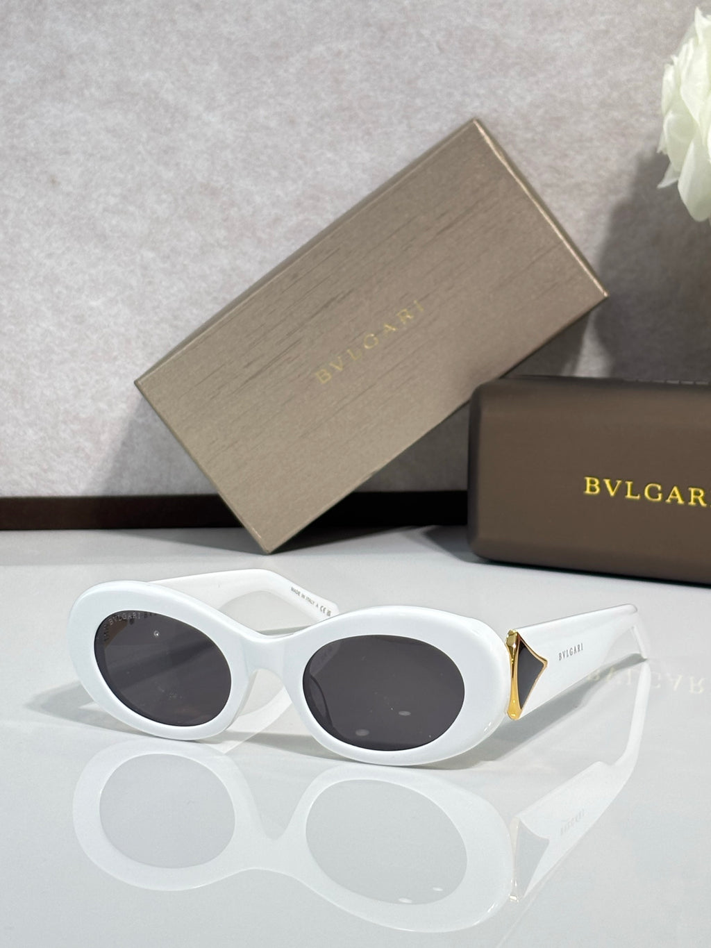 Bvlgari sunglasses with white frames, dark oval lenses, gold temple accents