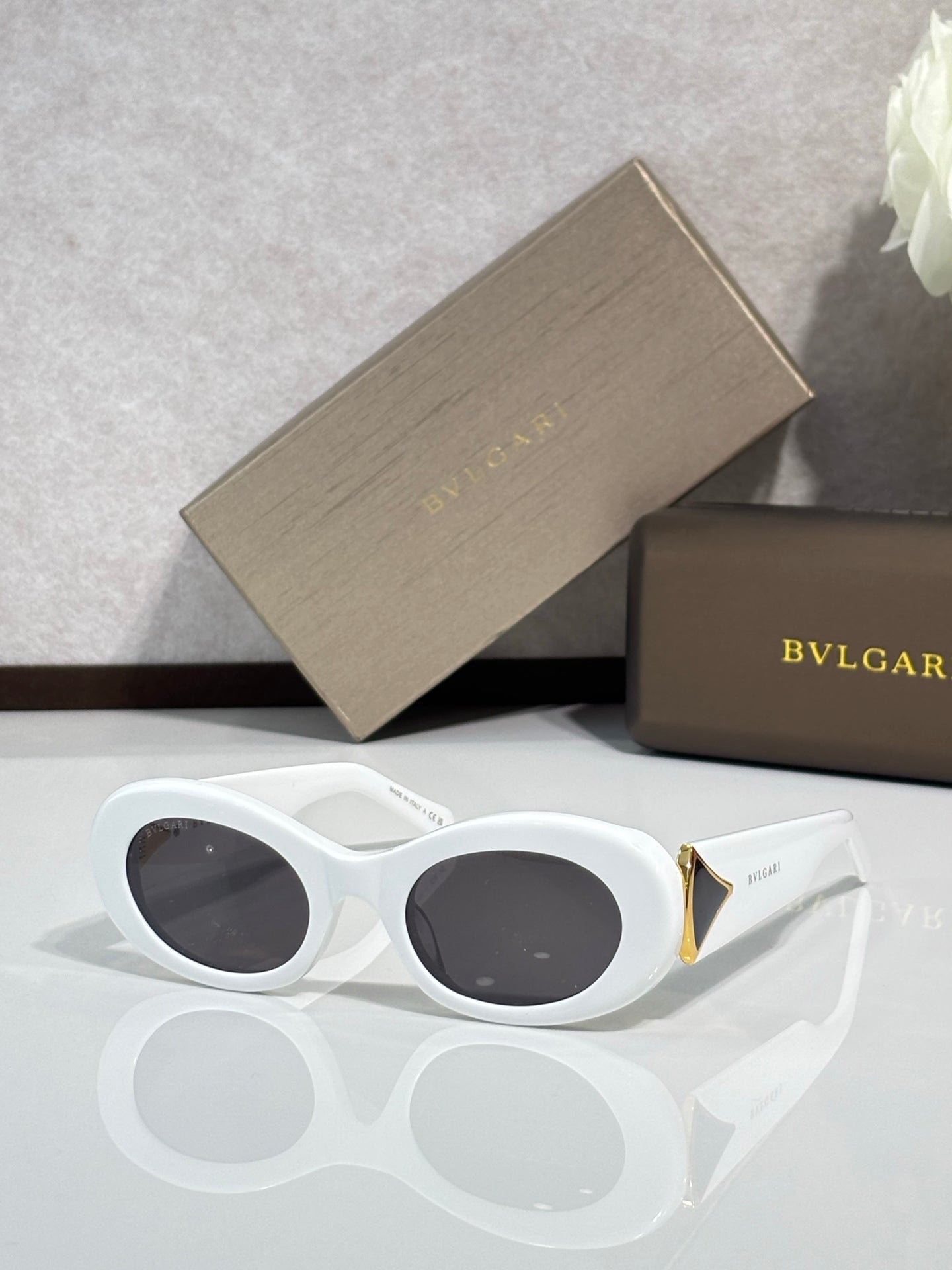 Bvlgari sunglasses with white frames, dark oval lenses, gold temple accents