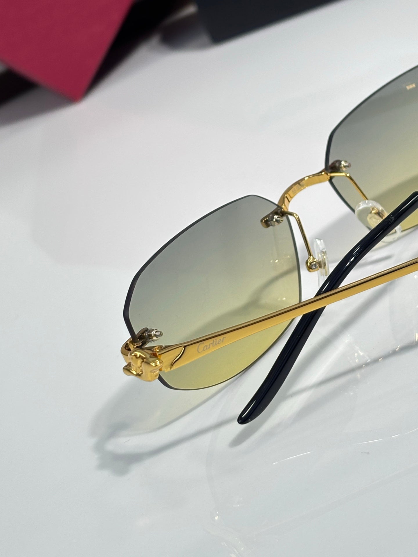 Cartier sunglasses close-up of lens: gold frame, dark temples, light amber tinted glass