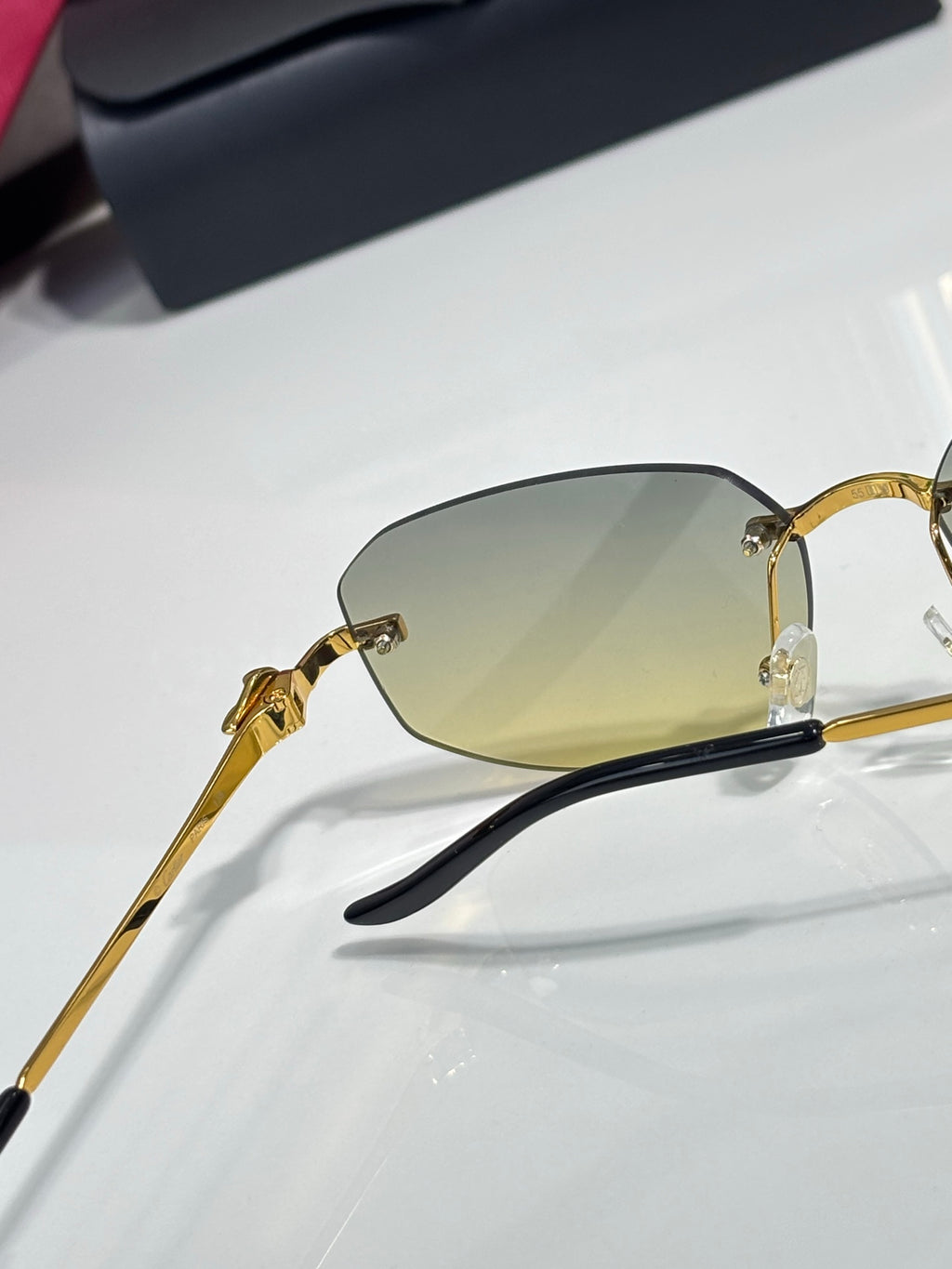Cartier sunglasses close-up side profile: gold metal frame with dark temples and amber lenses