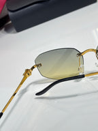 Cartier sunglasses close-up side profile: gold metal frame with dark temples and amber lenses