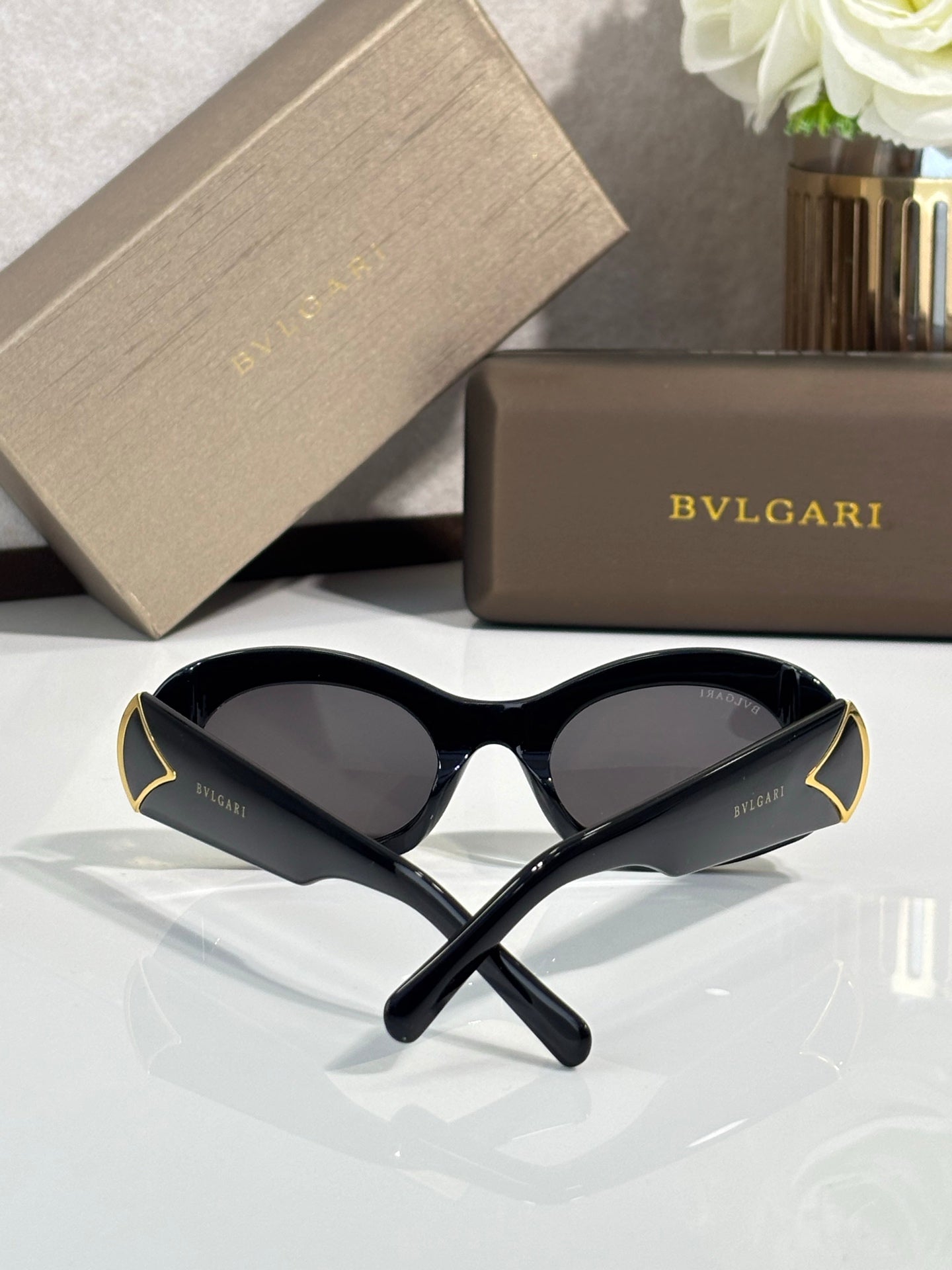 BVLGARI oval sunglasses with dark lenses, black frames and gold accent tips