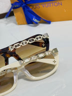 Sunglasses close-up: white frame with silver chain and charm details