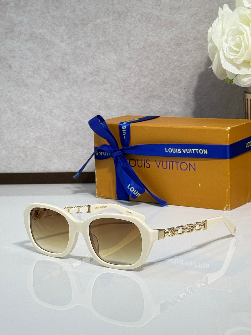 Sunglasses with white frame and tinted lenses, silver chain detail on arms