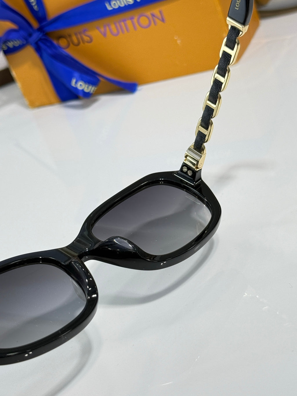 Sunglasses close-up: black frame with metal chain at lens bridge