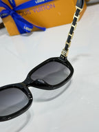 Sunglasses close-up: black frame with metal chain at lens bridge