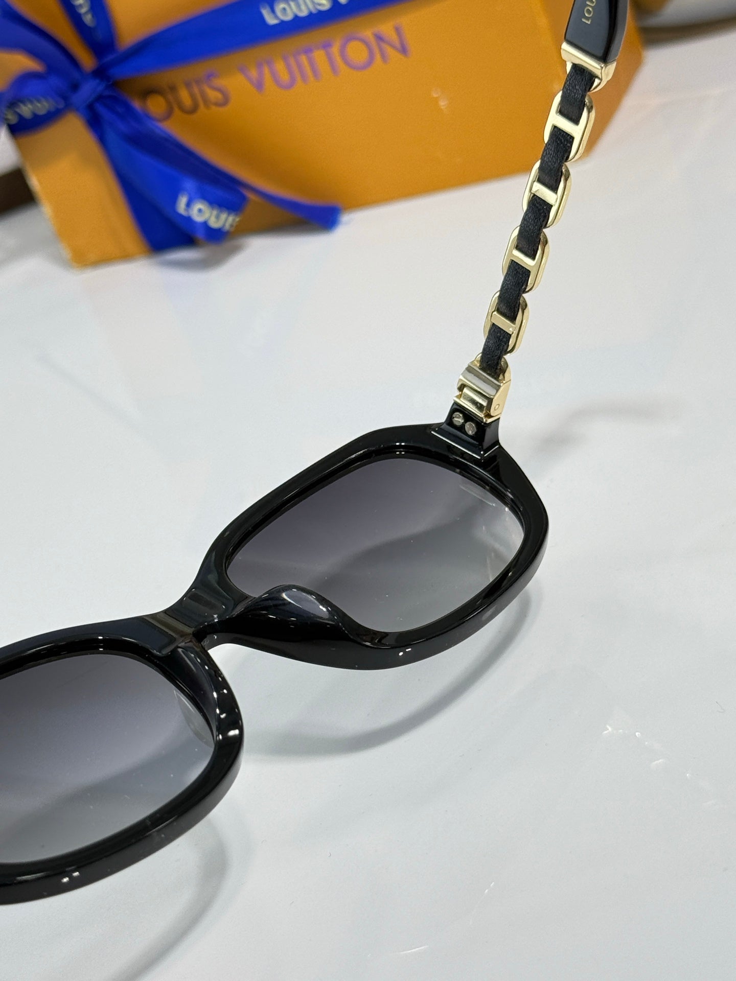 Sunglasses close-up: black frame with metal chain at lens bridge