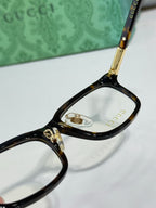 Close-up of black eyeglass frame with clear lens and gold-tone bridge hardware