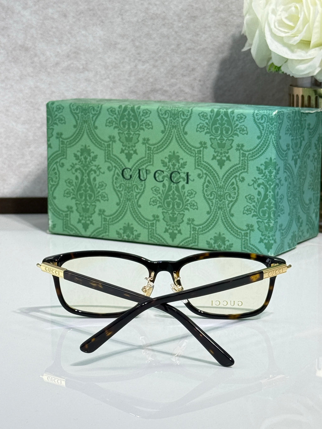 Gucci eyeglasses from above with black frames and gold-toned temple tips