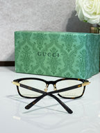 Gucci eyeglasses from above with black frames and gold-toned temple tips