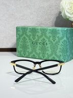 Black and gold eyeglasses with clear lenses and slim gold-tone top bar
