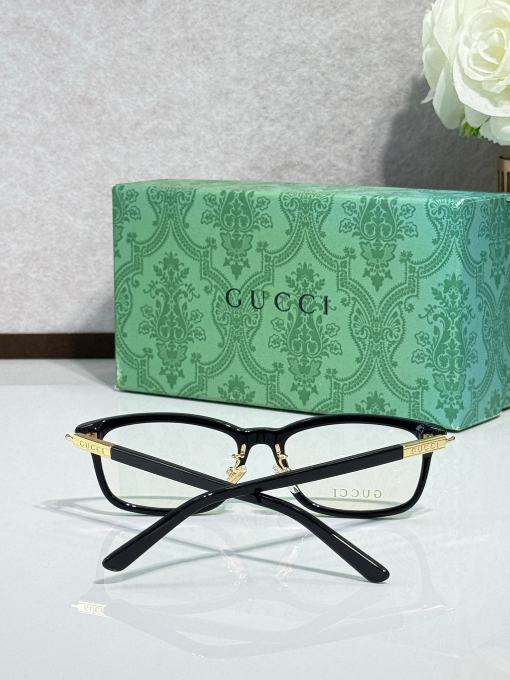 Gucci eyeglasses shown from above: black frames with gold bridge and temples
