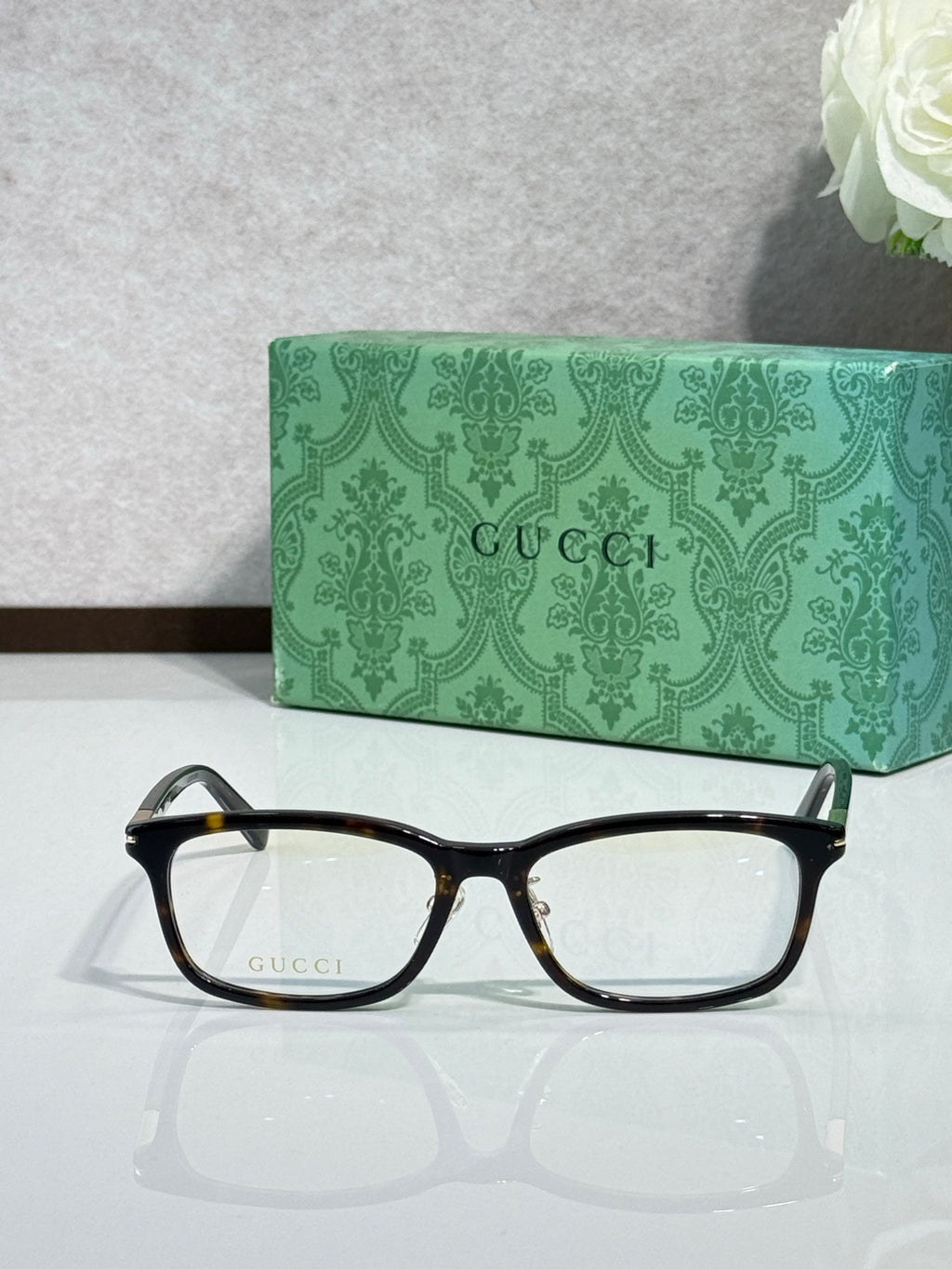 Gucci eyeglasses with black rectangular frames and clear lenses, gold logo on lens arm