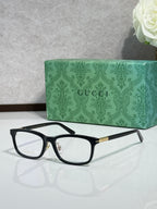 Black rectangular eyeglasses with clear lenses and gold-tone logo temples