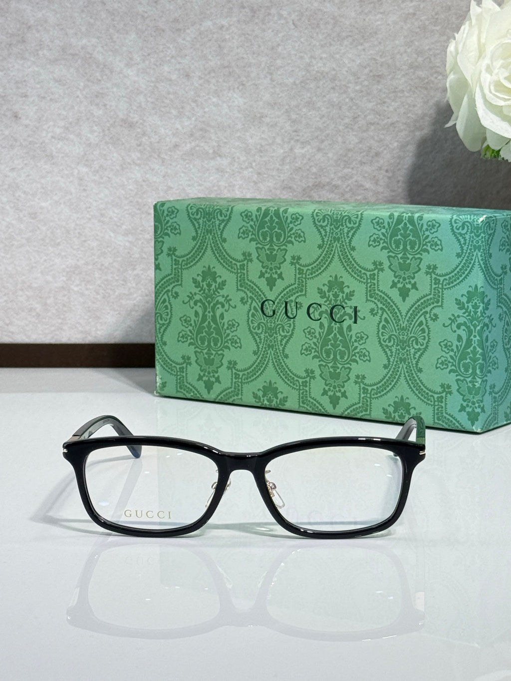 Black rectangular eyeglasses with clear lenses, gold-tone accents on temple arms