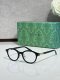 Black eyeglass frames with clear lenses and gold logo temples.